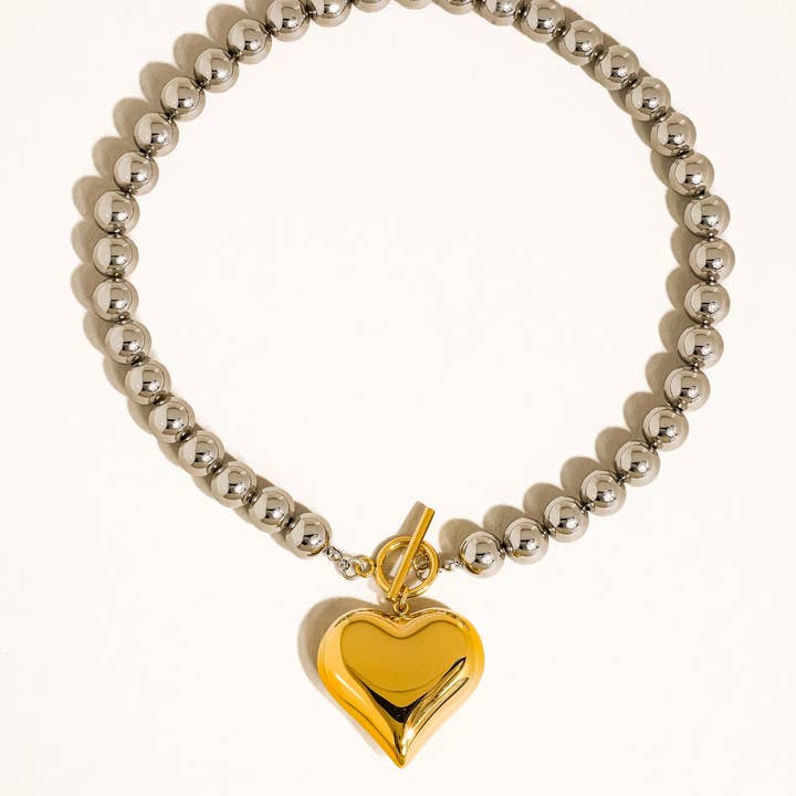 Raissa Two Tone Heart Necklace by Flanerie by MAIQ featuring a silver ball-bead chain, an 18K gold heart pendant with a non-tarnish finish, and a toggle clasp.