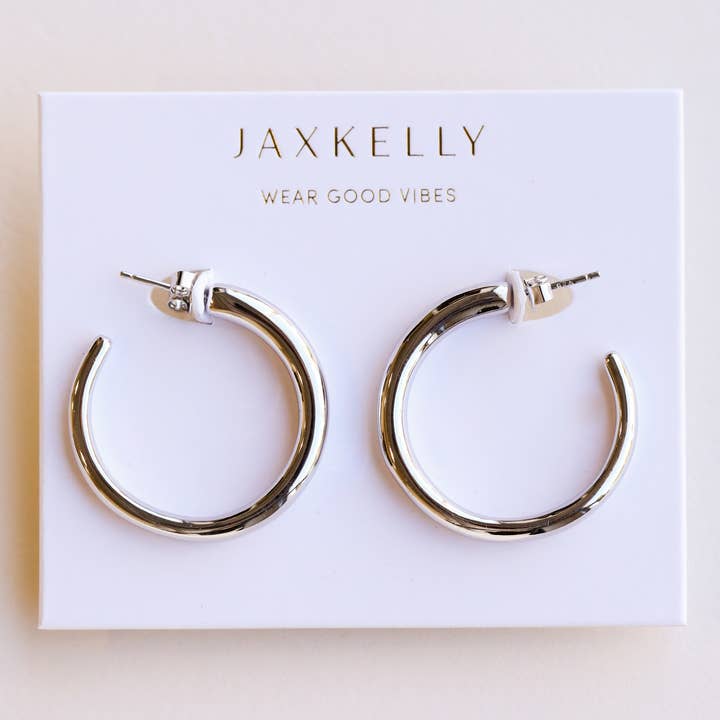 JaxKelly Everyday Silver Hoop Earrings by JaxKelly, featured on a white card with “Wear Good Vibes” printed above, are the perfect tarnish-free accessory for your daily style.