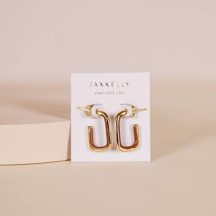 A pair of JaxKelly Brown Enamel Large Rectangle Gold Hoop Earrings sits upright on a white JaxKelly card against a beige background. Hypoallergenic.