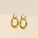 A pair of Gold Hoop Coupled Earrings by JaxKelly, crafted in 18kt gold, displayed against a neutral beige background.