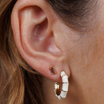 Close-up of a person's ear wearing two earrings: a small rectangular stud and a larger JaxKelly Vintage Hoop earring.
