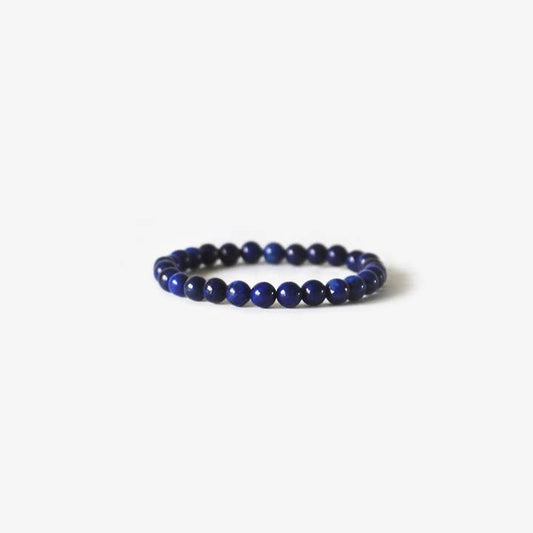 The Earth Bracelet - Blue Lapis by BRANCO features round dark blue lapis beads on an elastic band, shown against a plain white background.