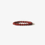 The Earth Bracelet - Red Jasper by BRANCO features small, round red jasper beads arranged in a circle and is displayed on a white background.