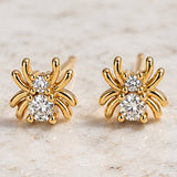 Mesa Blue Tiny Cz Spider Stud Earrings feature multiple legs and two clear round cubic zirconia gemstones on each earring, crafted from tarnish-resistant 18K gold plated metal. Displayed on a light stone surface, these unique studs from Mesa Blue offer an elegant touch and lasting shine.