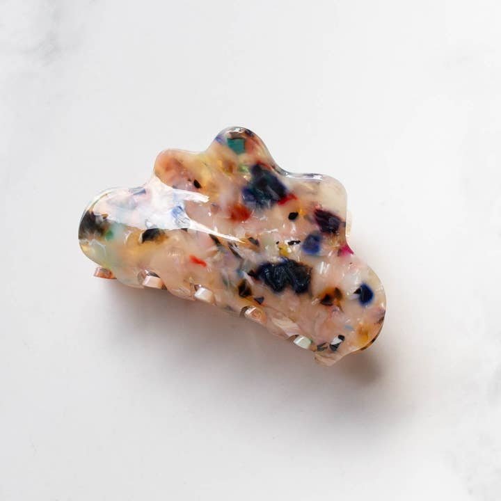 The Eco Cloud Hair Claw Clip by Tiepology features a multicolored marbled pattern and cloud shape, making this eco-friendly accessory both stylish and sustainable. It’s shown resting on a white surface.