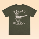 Olive green illustrative Roadrunner vs. Rattlesnake t-shirt by Ballad Originals, featuring a bird graphic and the text “BALLAD of the BIRD DOG Trust Your Gut” on the back, displayed flat on a tan background.