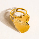 Sefina Locket Heart Ring by Flanerie by MAIQ, a gold-toned adjustable ring featuring a locket charm with ornate filigree edges.