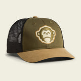 The El Mono Standard Hat by Howler Brothers is an olive green and tan trucker hat with a black mesh back, featuring an embroidered gorilla face logo inspired by Howler artwork and an adjustable snapback closure for the perfect fit.