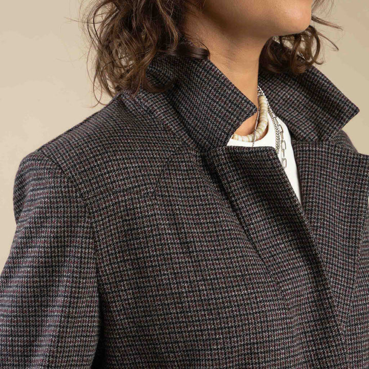 Close-up of a person wearing the Eleanor Relaxed Western Blazer by Sendero Provisions Co., styled with a popped collar, layered necklaces, and a white top underneath.