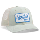 The Electric Standard Hat by Howler Brothers is a light-colored mesh trucker with a solid front and brim, blue and white "Howler Bros" patch, medium crown, adjustable fit, and is part of the Howler Brothers hat collection.