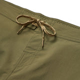 Close-up of Howler Brothers Electrolight Tech Pants in olive green, featuring a front pocket and a tan drawstring tied at the waistband.