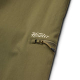 Close-up of an olive green nylon ripstop pocket with a zipper and "Howler" printed in white above, from the Electrolight Tech Pants by Howler Brothers.