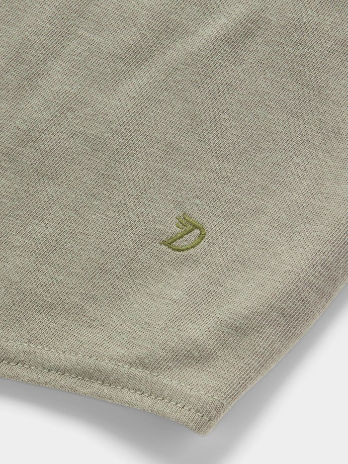 Close-up of the ultra-soft, light olive green Essential drirelease® Tank by Duck Camp, featuring a small embroidered "D" with a crown near the hem.