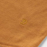 Close-up of the orange Essential drirelease® Tank by Duck Camp, made from ultra soft fabric and featuring a small yellow embroidered fox head logo near the hem.