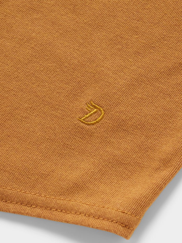 Close-up of the orange Essential drirelease® Tank by Duck Camp, made from ultra soft fabric and featuring a small yellow embroidered fox head logo near the hem.
