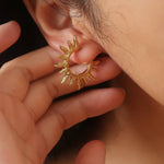 Sablière Sunburst Hoop Earrings featuring a hypoallergenic gold hoop with a textured sunburst design worn on an earlobe.