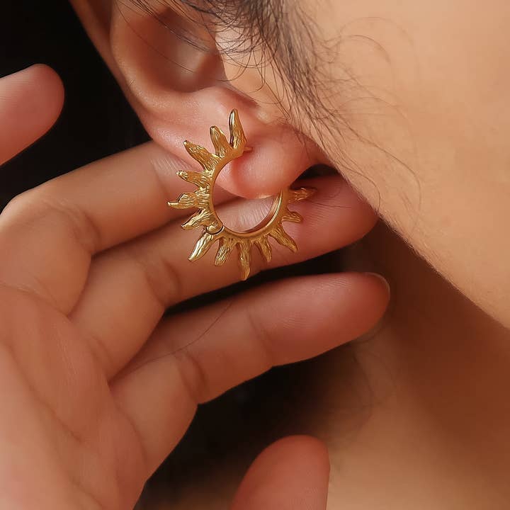Sablière Sunburst Hoop Earrings featuring a hypoallergenic gold hoop with a textured sunburst design worn on an earlobe.