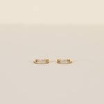 A pair of Double Champagne Hoop earrings by JaxKelly, featuring small gold double hoops adorned with two rows of shimmering pave stones, displayed against a plain beige background.
