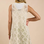 A woman is shown from the back wearing a Sadie And Sage Fell For You Crochet Front Tie Cardigan in cream, size small, layered over a white top and light green pants against a beige background.