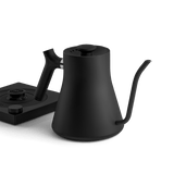 The Fellow Electric Kettle features a matte black finish, temperature control, and a precision pour spout. Shown on its matching base against a white background.