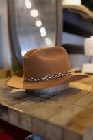 The Easy Drifter Felt Hat | Whiskey LBJ, inspired by the LBJ style and featuring a patterned band, rests on a wooden surface in-store.