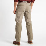 Person wearing Duck Head Field Canvas Briar Pants in khaki, paired with a brown belt, brown shoes, and a maroon shirt, standing with their back to the camera.