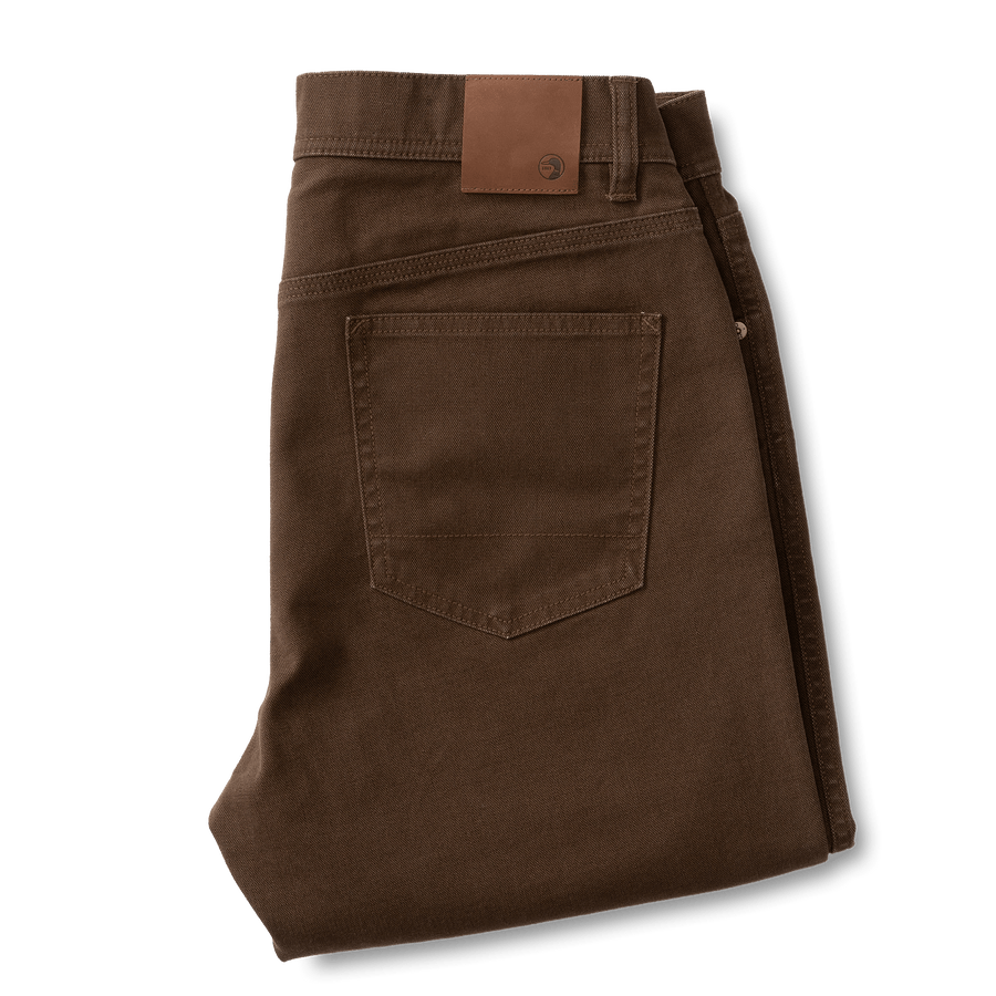 A pair of Duck Head Field Canvas Five-Pocket pants in brown, neatly folded, with a back pocket and a brown leather patch on the waistband.