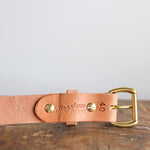 A close-up of the Field Duty Belt by Ballad of the Bird Dog, crafted from tan Wickett & Craig vegetable tanned leather with brass hardware, stamped "40" and "BROWN", shown on a wooden surface.