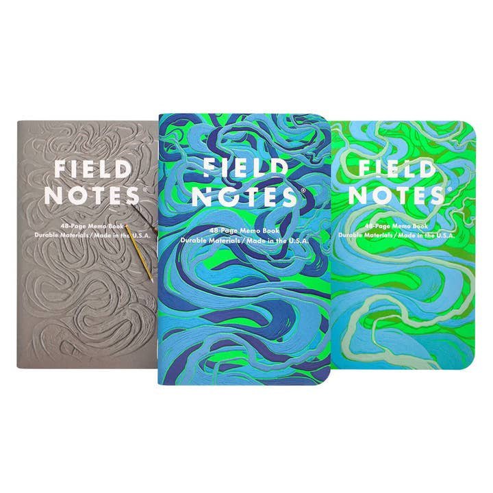 The Is a River Alive? | Field Notes 3-Pack features abstract gray, blue, and green textured embossed covers, displayed side by side for a distinctive look.