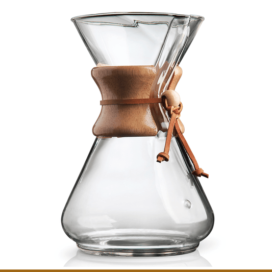 The Chemex Filter Drip Coffeemaker (CM-10A) features a clear glass design with a wooden collar and leather tie. This elegant 50 oz brewer by Chemex is shown against a white background.