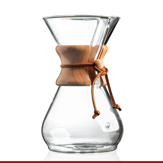 The Chemex Filter Drip Coffeemaker (CM-8A) features a glass body with a wooden collar and leather tie. This stylish eight-cup, 40-ounce coffee maker by Chemex is shown on a white background.