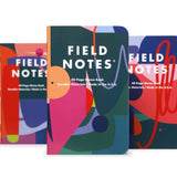 Three vibrant "Flora | Field Notes" Memo Books by Field Notes, inspired by the Roman goddess Flora, stand upright with abstract covers that evoke creativity and renewal. The center notebook is slightly in front for emphasis.
