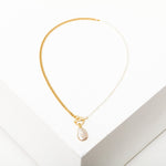 The Fonda Half Chain Pearl Necklace by Larissa Loden features a gold plated half chain, half freshwater pearls, and a single oval pearl pendant, beautifully displayed on a white surface.