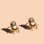 The Peter and June Fortune Beetle Studs, 18k gold plated and beetle-shaped, are shown against a plain beige background.