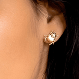 Close-up of a person's ear wearing the Fortune Beetle Studs by Peter and June, 18k gold plated and beetle-shaped.
