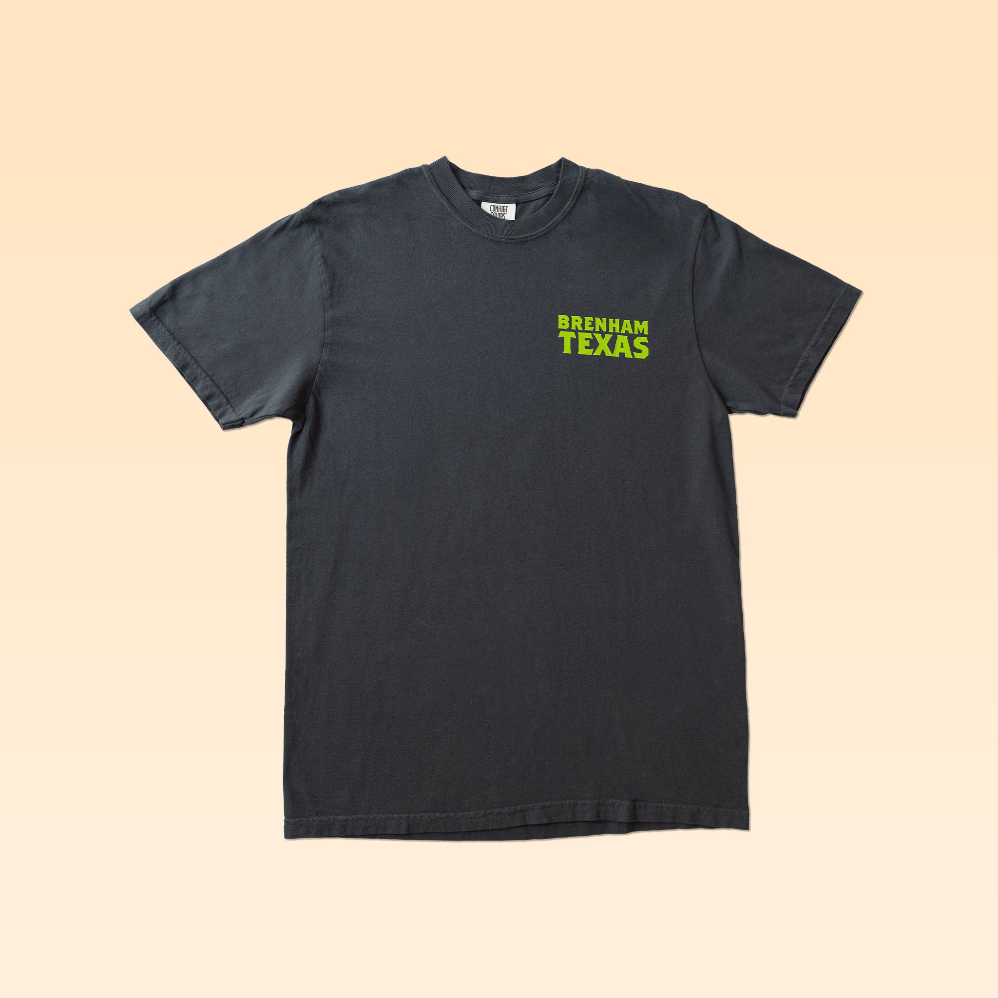 A plain black Bluebonnet Country Shirt by Ballad Originals with “Brenham Texas” printed in bright green text on the upper left chest, featuring quality construction and a comfortable everyday fit, displayed on a light beige background.