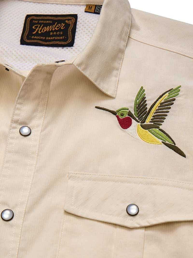 The Howler Brothers Gaucho Snapshirt | Nectar Seekers features a beige design with embroidered hummingbird art above the left chest pocket and a visible brand label inside the collar—a fresh update to the classic western shirt.
