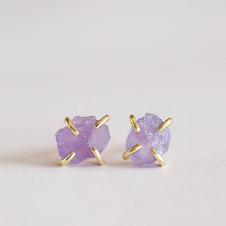 The Gemstone Prong - Amethyst - Gold Earrings by JaxKelly feature raw amethyst studs in gold prongs, offering elegant, hypoallergenic jewelry displayed on a plain white background.