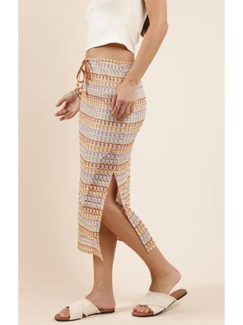 Woman wearing the Sadie And Sage Gilded Sky Midi Skirt with spandex lining and side slit, styled with a white sleeveless top and white slide sandals, standing against a neutral background.