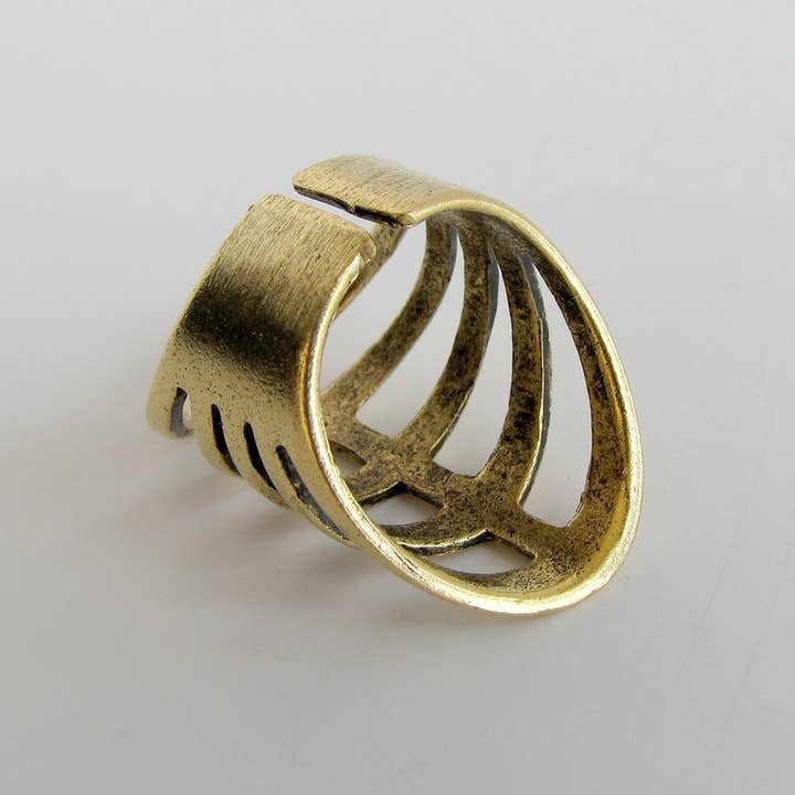 The Gladiator Ring by Ornamental Things is a 24kt gold plated, open-ended ring with a wide band and ribcage-inspired cutout, shown on a plain white surface.