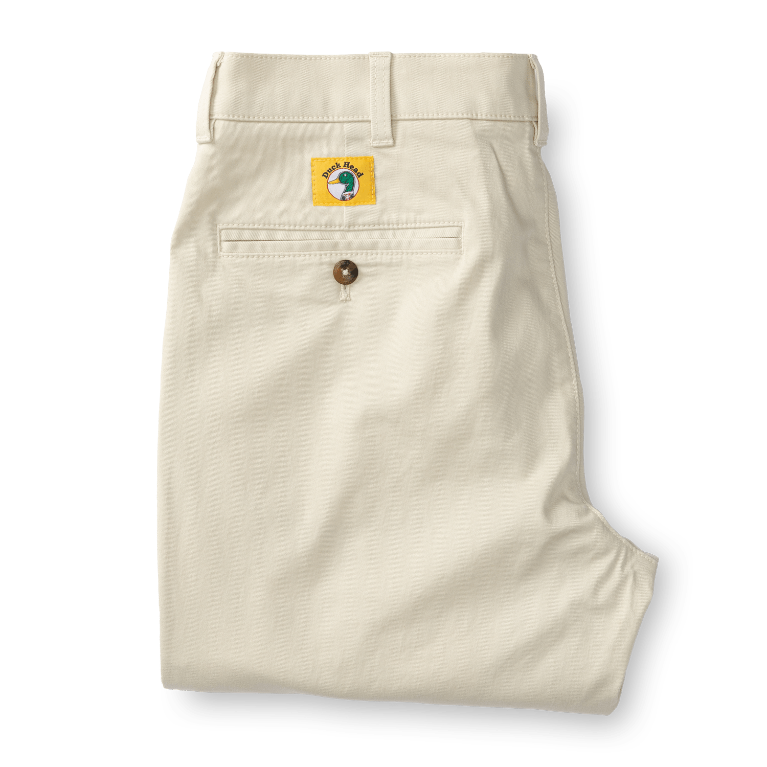 The Duck Head Gold School Chino (Big Gold Patch) features cream-colored khakis with a single back pocket, button, and a yellow patch with a green fish, celebrating classic American style.