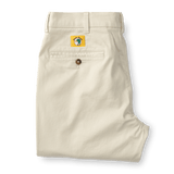 The Duck Head Gold School Chino (Big Gold Patch) features cream-colored khakis with a single back pocket, button, and a yellow patch with a green fish, celebrating classic American style.