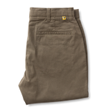 A pair of Gold School Chino pants by Duck Head in olive green cotton twill, neatly folded, with belt loops, back pocket stitching, and a small yellow Duck Head tag above the pocket.