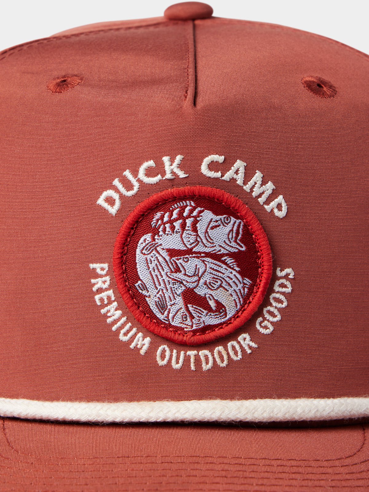 Close-up of the Duck Camp Grandpa Hat | Bass Trinity, a rust-colored snapback featuring a circular patch with an embroidered duck and "Premium Outdoor Goods." Adjustable snapback provides a comfortable fit.