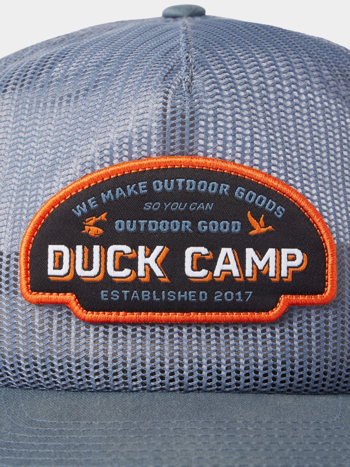 Close-up of the Duck Camp Gulf Trucker | Cast & Blast mesh hat, featuring a patch with “Duck Camp. We make outdoor goods so you can outdoor good. Established 2017.” Breathable and adjustable snapback for a perfect fit.