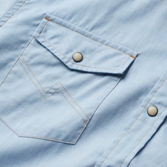Close-up of the H Bar B Snapshirt in Faded Blue Oxford by Howler Brothers, featuring a pocket with a flap, decorative stitching, and classic pearl snaps.