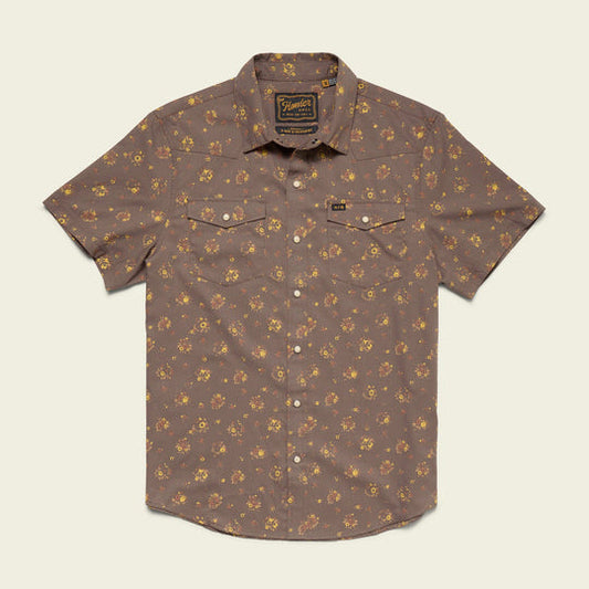 The H Bar B Snapshirt by Howler Brothers is a brown short-sleeve western shirt with a small yellow and orange floral pattern, two chest pockets, and a collar, laid flat on a light background.