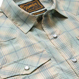 The H Bar B Snapshirt by Howler Brothers features a light green and beige plaid, pearl snaps, two front pockets, and "Howler Bros" branding on the inside collar tag.
