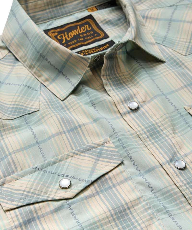 The H Bar B Snapshirt by Howler Brothers features a light green and beige plaid, pearl snaps, two front pockets, and "Howler Bros" branding on the inside collar tag.