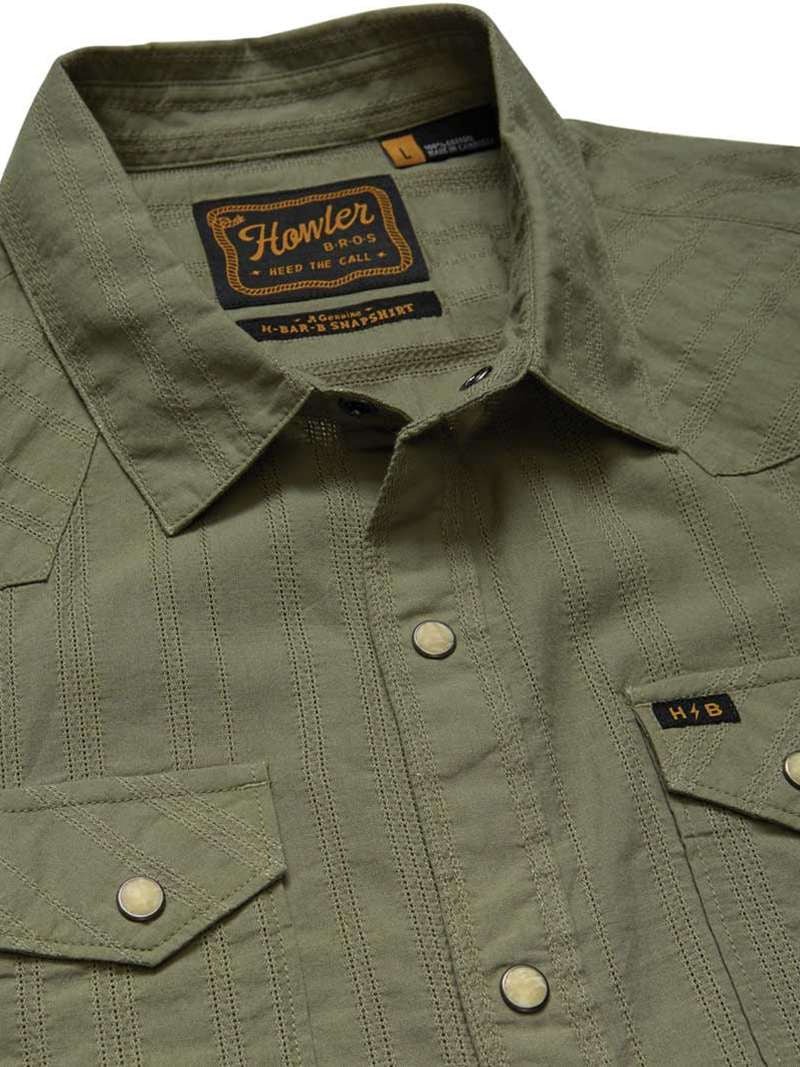 Close-up of the olive green H Bar B Snapshirt by Howler Brothers, featuring pearl snaps, two chest pockets, and a visible brand label on the inside collar.